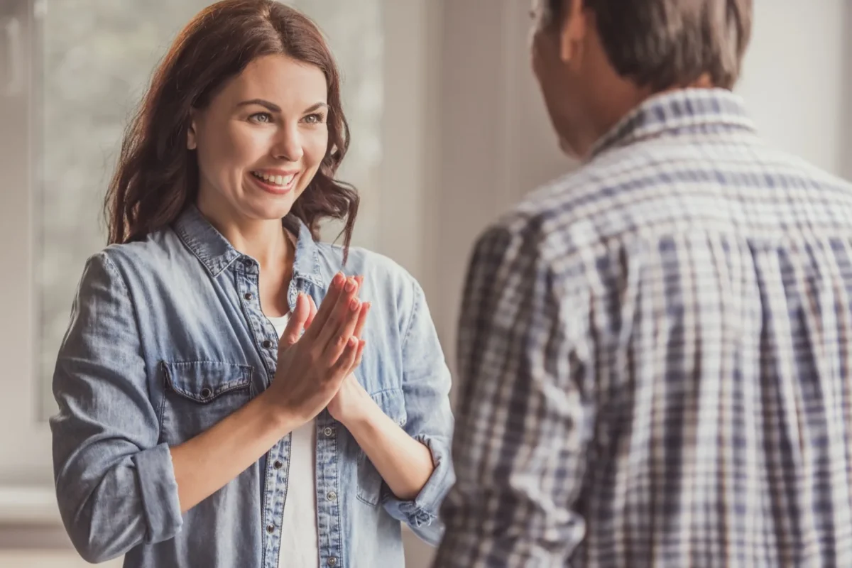 woman with hands clasped apologizing to man