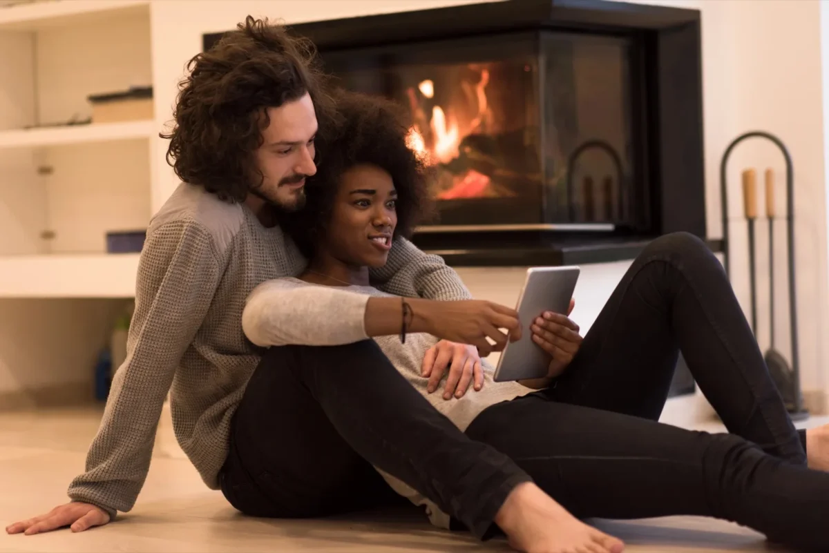 8 Unmistakable Body Language Signs He's Interested In You couple cuddling and reading tablet together