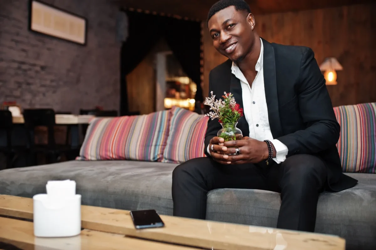 man sitting on couch holding flowers
