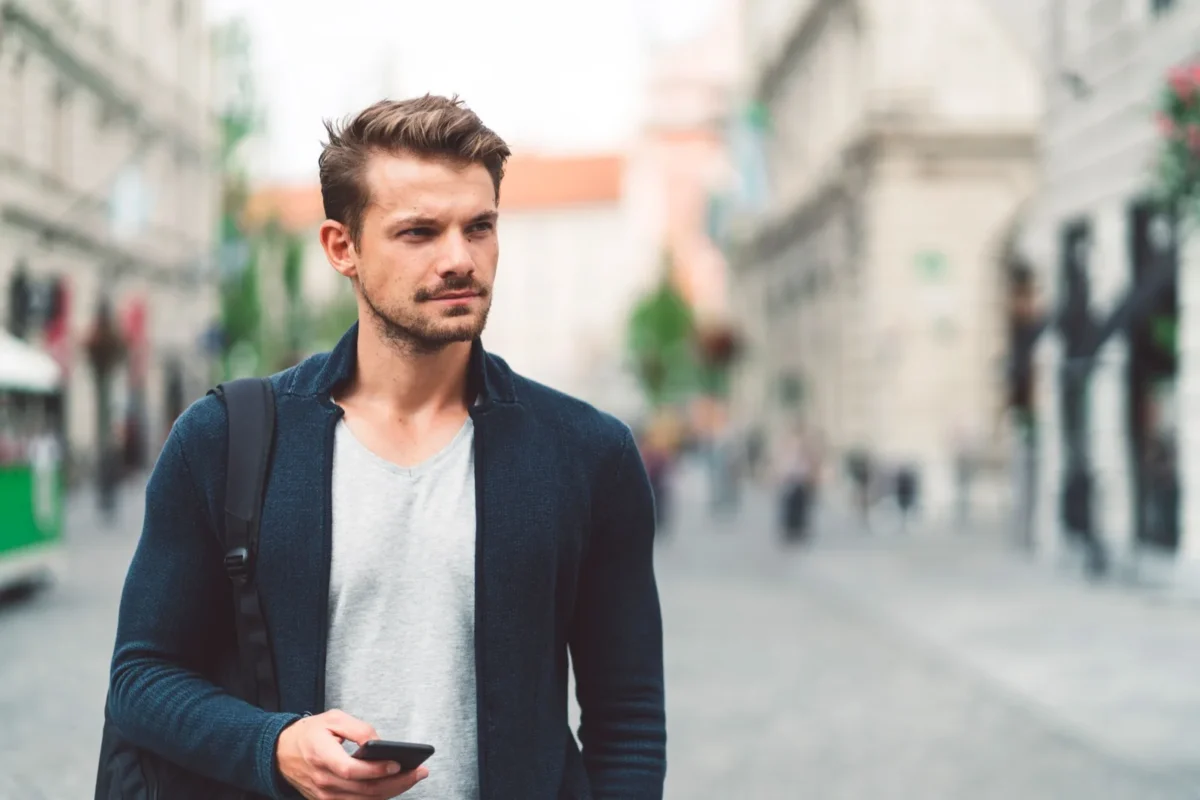 man holding phone standing in street