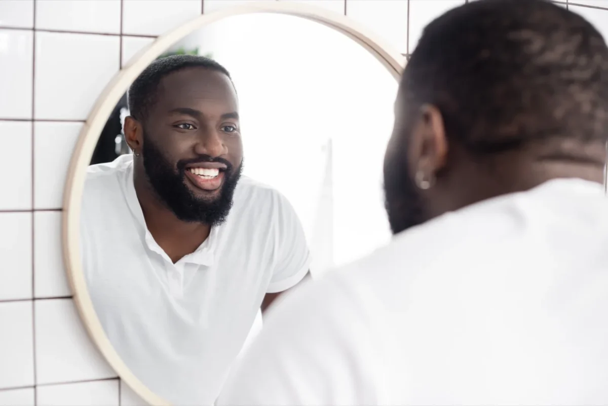 8 Unmistakable Body Language Signs He's Interested In You man looking into mirror while smiling