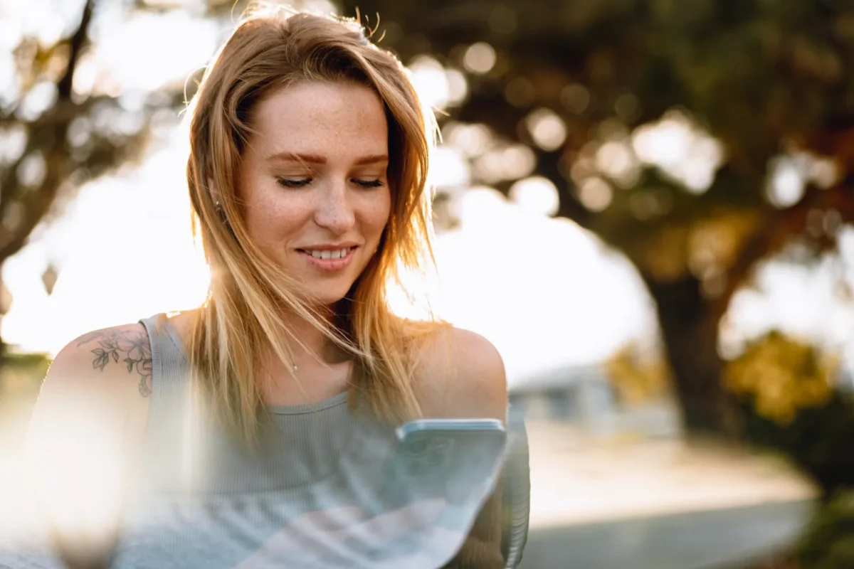7 Powerful Ways To Make Him Miss You Like Crazy woman smiling and holding phone