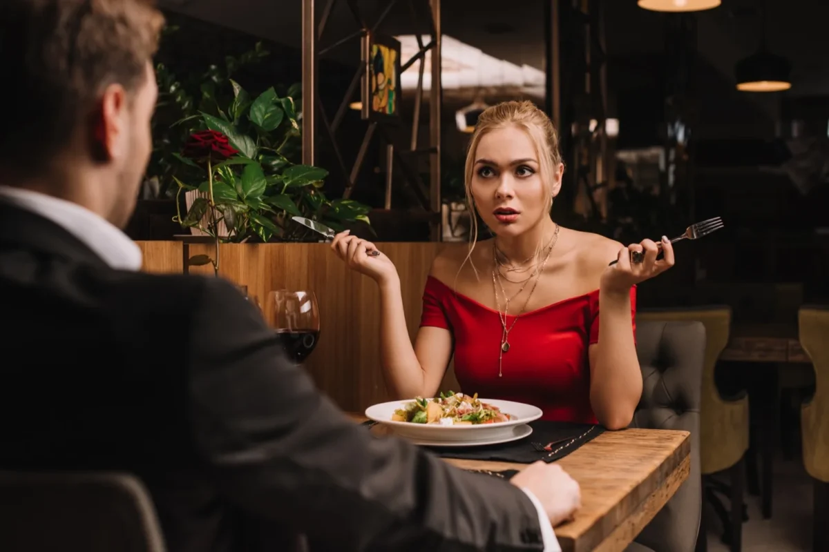 10 Things Single Women Are SO Tired of Hearing (And How To Fire Back) woman frustrated on bad date holding silverware