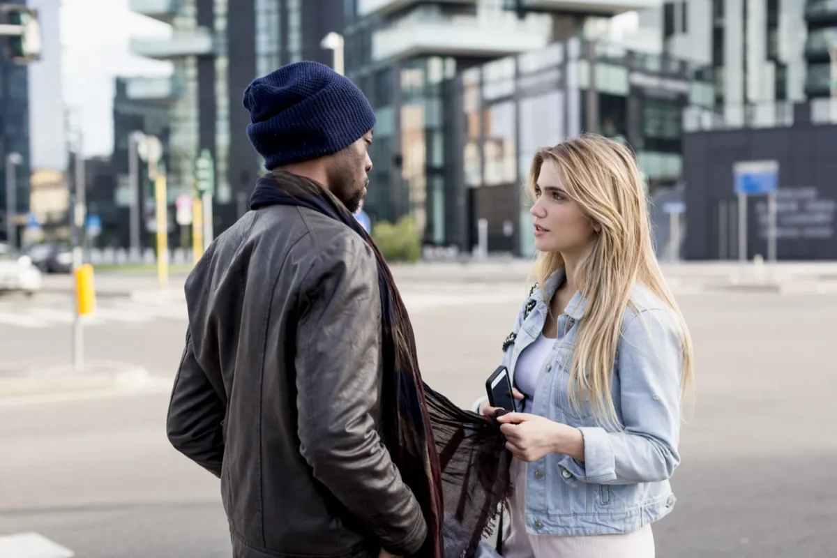 couple standing on street woman holding onto guy's scarf