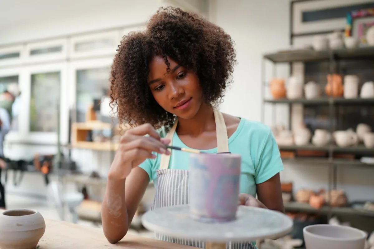 woman painting ceramic pot