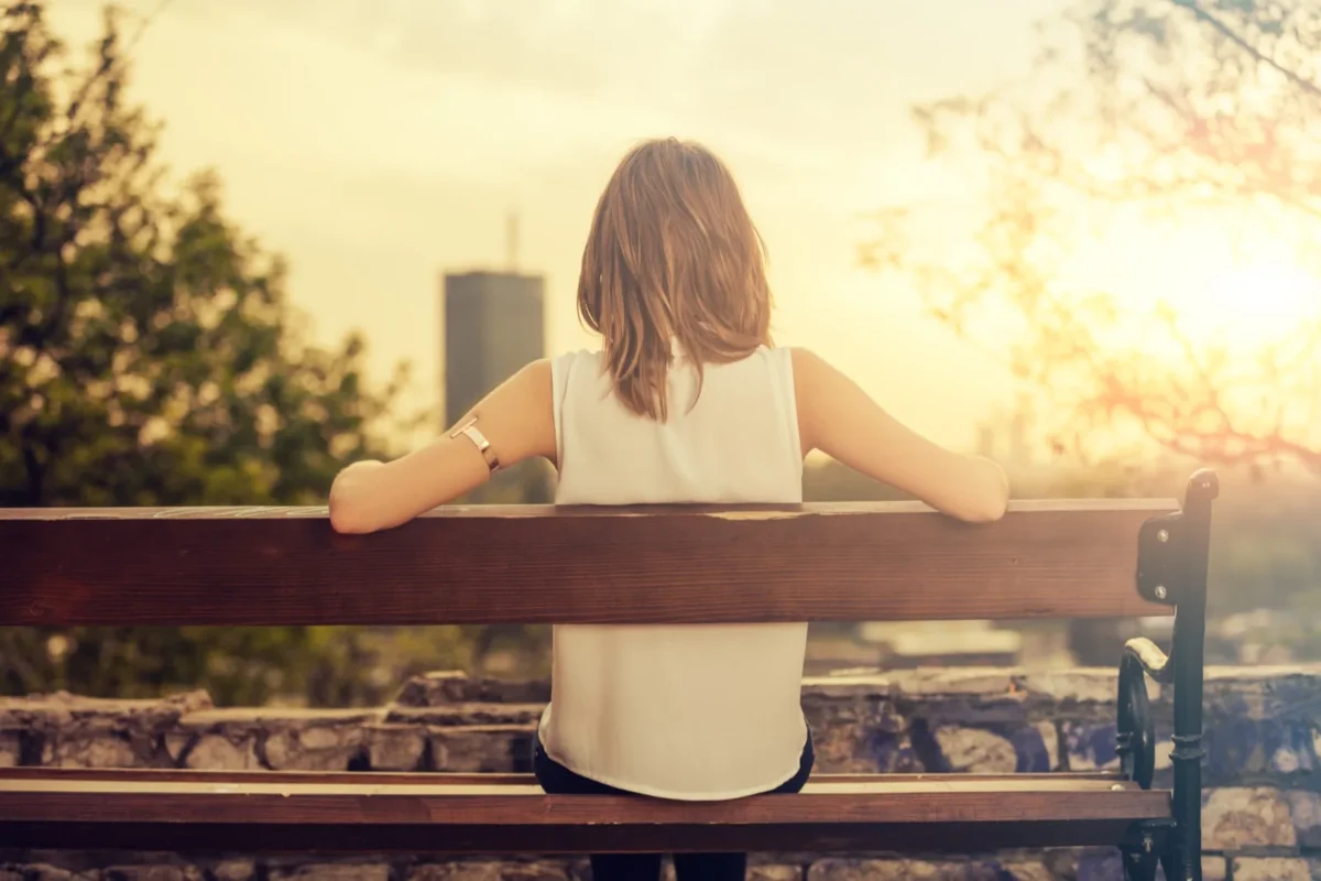 woman sitting on park bench back turned