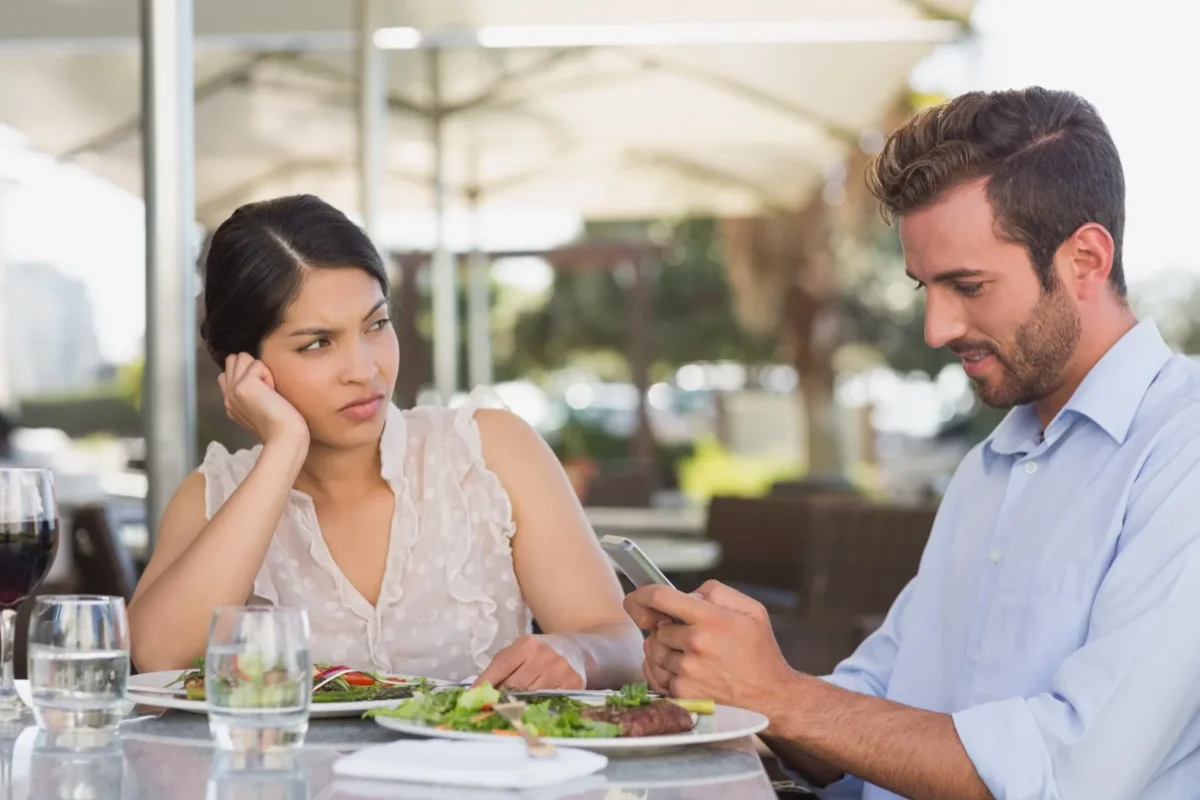6 Reasons Why Women Lose Interest At The Beginning man focusing on phone being rude to woman on date