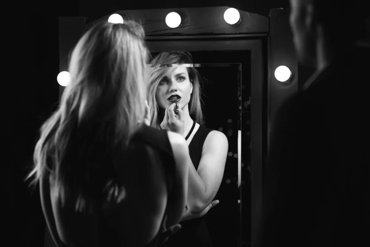 woman doing her lipstick with man watching in mirror