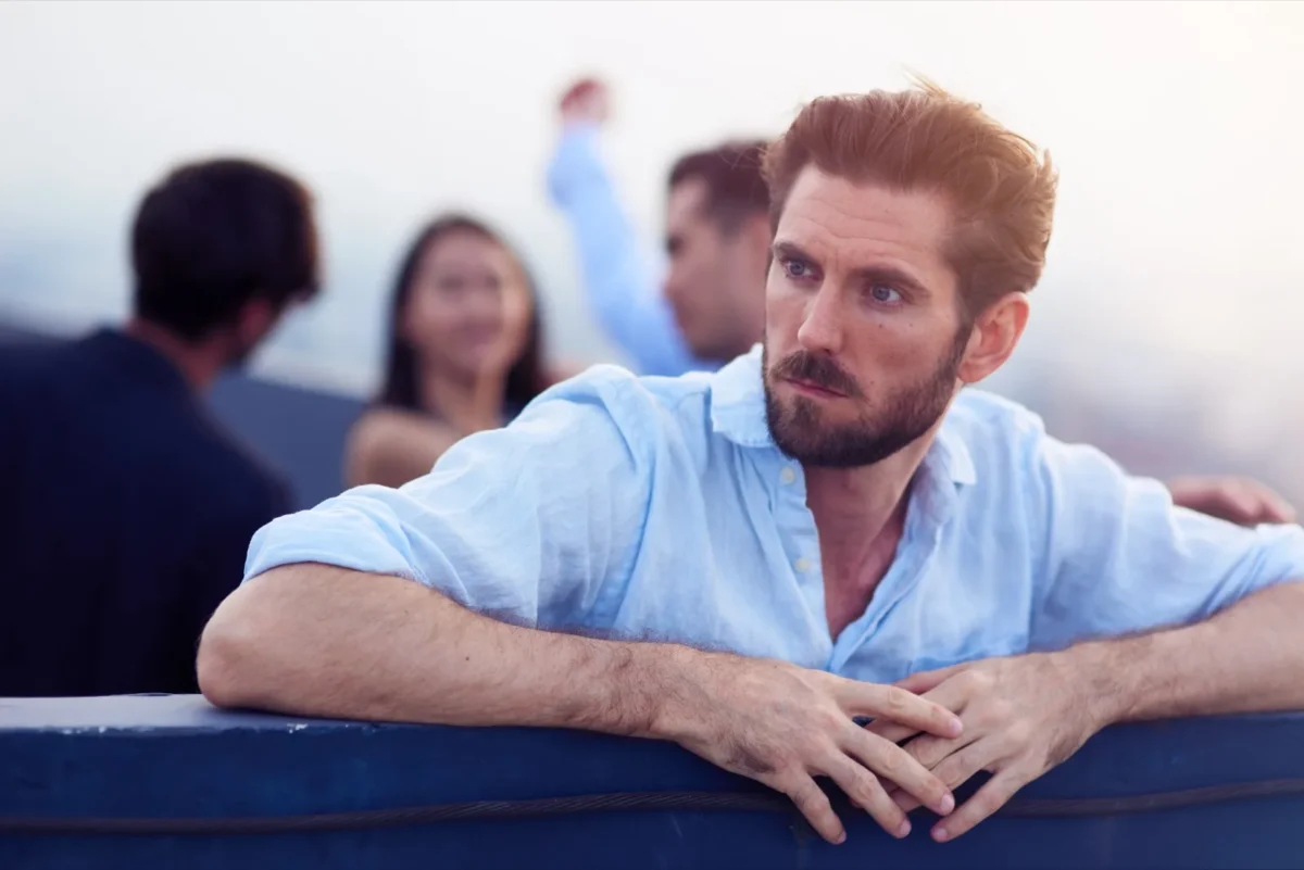 man looking away from people having a good time