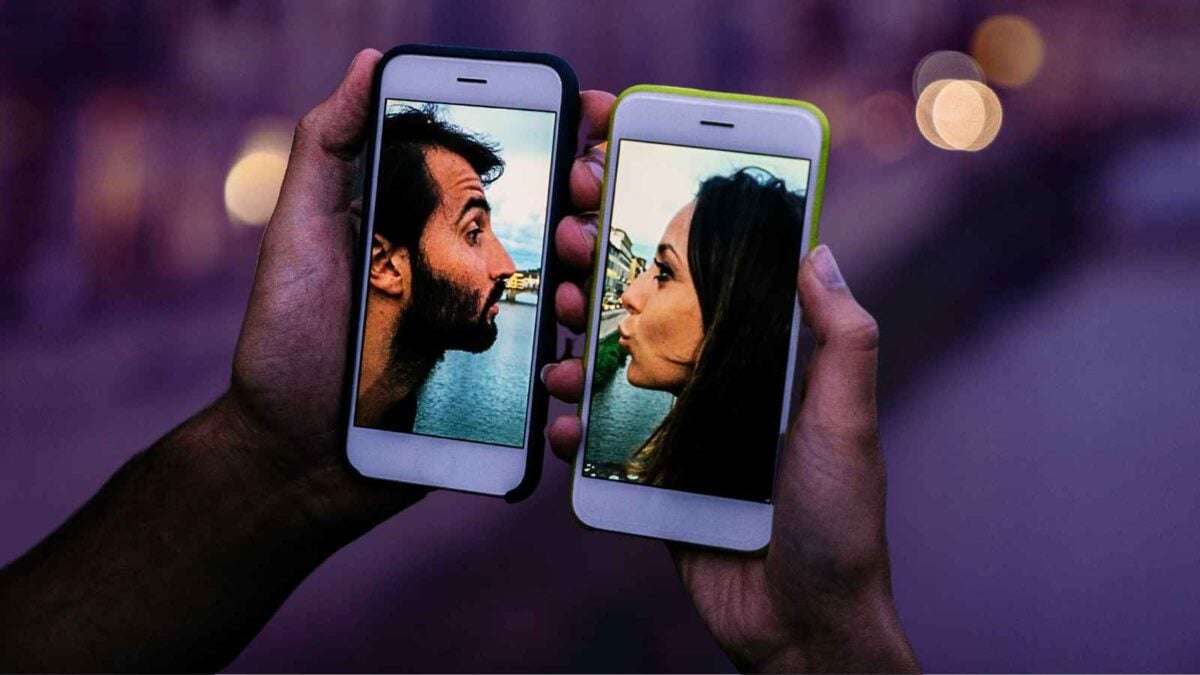 2 phones with couple kissing through them