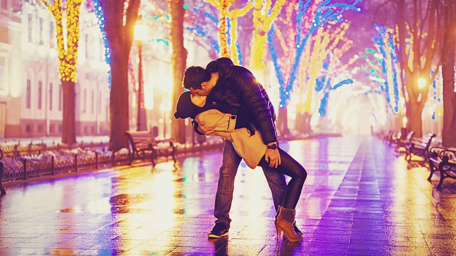 man kissing woman on street at night