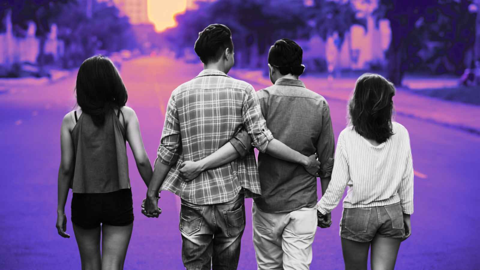 four people walking down steet holding hands