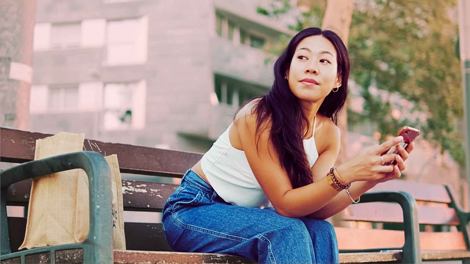 woman holding phone sitting on bench