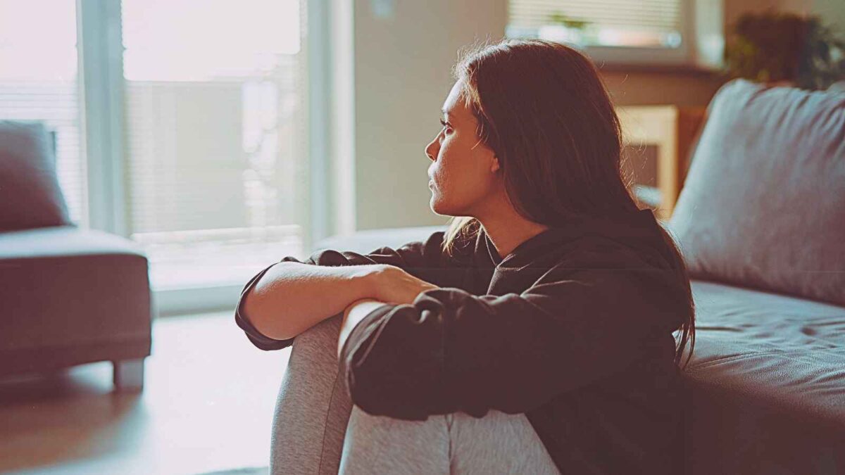 woman sitting on floor looking out window