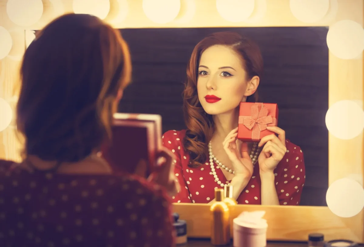 You Can Enjoy Being Objectified. It'll Still Wreck Your Relationship. woman looking into mirror holding gift box