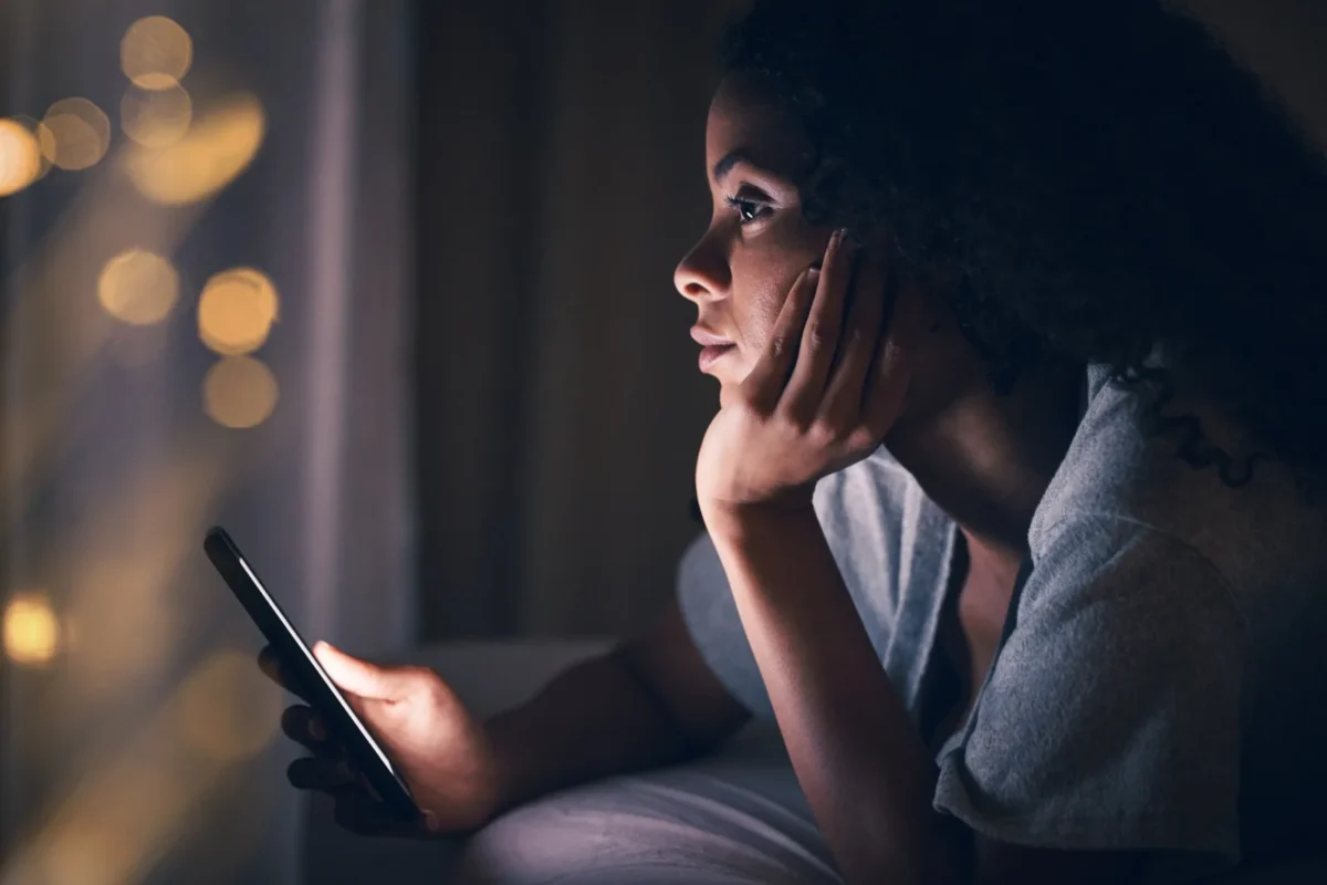 contemplative woman in bed with phone